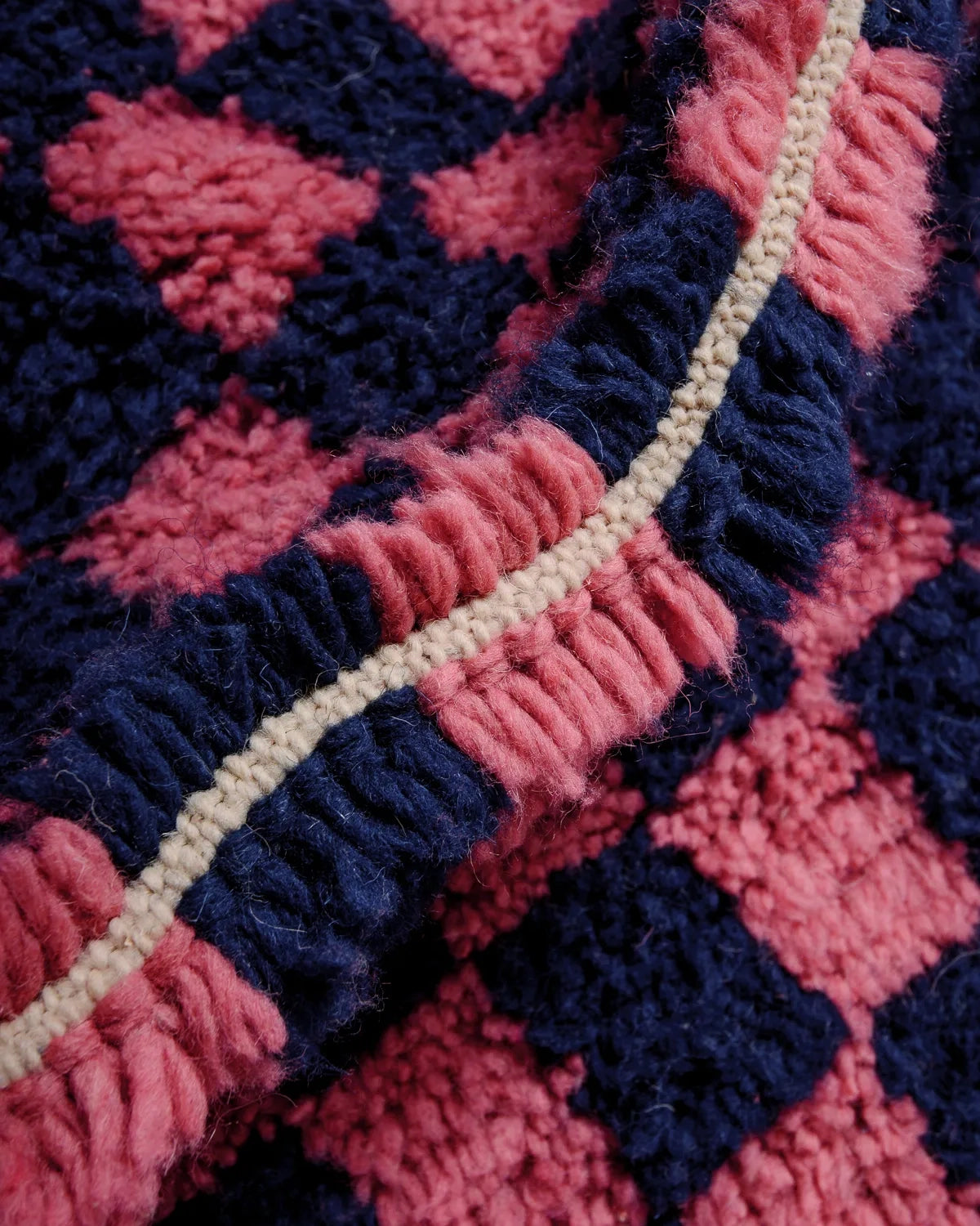 Detail of thick wool in Beniourain rug with a navy and dark pink checkered pattern.